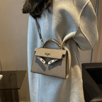 Sac à main en cuir taupe porté par une femme en manteau beige, style élégant et moderne, accessoire de mode tendance, luxe et sophistication.