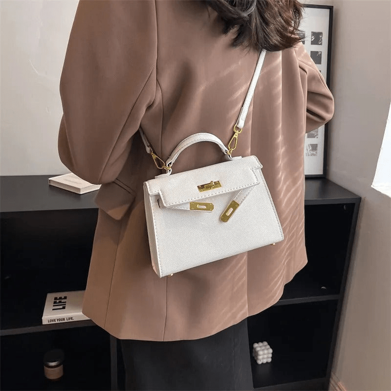 Femme portant un sac à main blanc élégant, style Kelly, avec une veste marron. Accessoire de mode chic, tendance et sophistiqué pour femmes.
