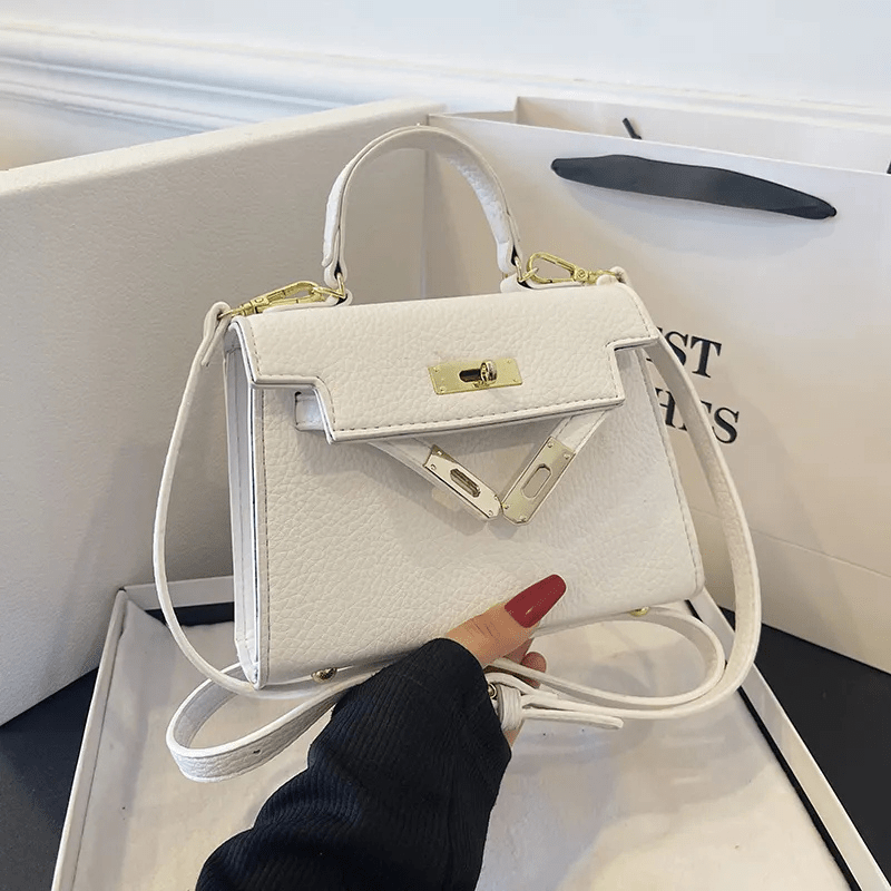 Sac à main blanc élégant avec détails dorés, posé dans une boîte. Design chic et moderne, idéal pour la mode féminine. Accessoire tendance.