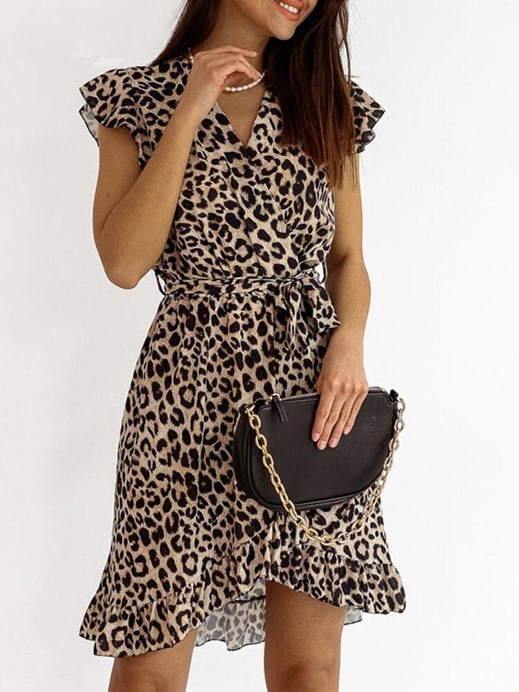 Robe à imprimé léopard avec ceinture, portée par une femme tenant un sac noir à chaîne dorée. Mode féminine tendance, style animalier chic.
