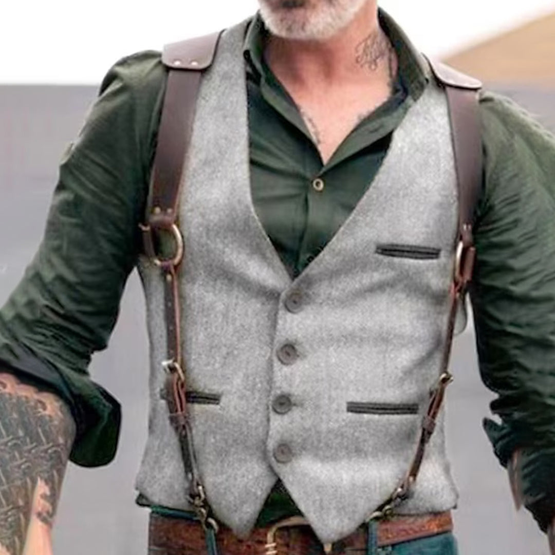 Homme portant un gilet gris élégant avec chemise verte et bretelles en cuir, style vintage chic, mode masculine tendance, tatouages visibles.