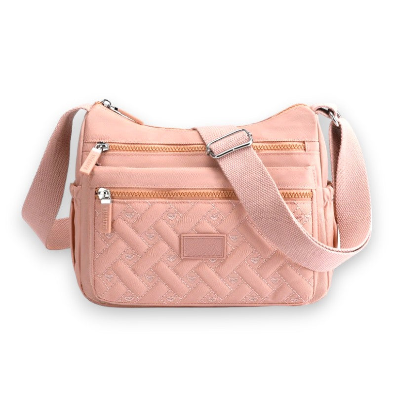 Sac à bandoulière rose en tissu matelassé avec poches zippées, sangle ajustable et design élégant. Accessoire mode femme tendance et pratique.