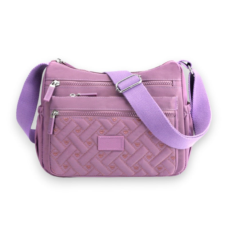 Sac à bandoulière violet en tissu avec motif tressé, plusieurs poches zippées et sangle ajustable. Accessoire mode femme tendance et pratique.