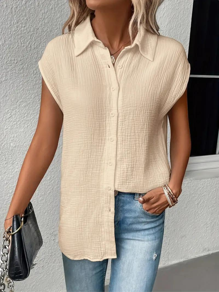 Femme portant une chemise beige texturée à manches courtes, associée à un jean bleu clair. Mode décontractée, style estival, tendance féminine.