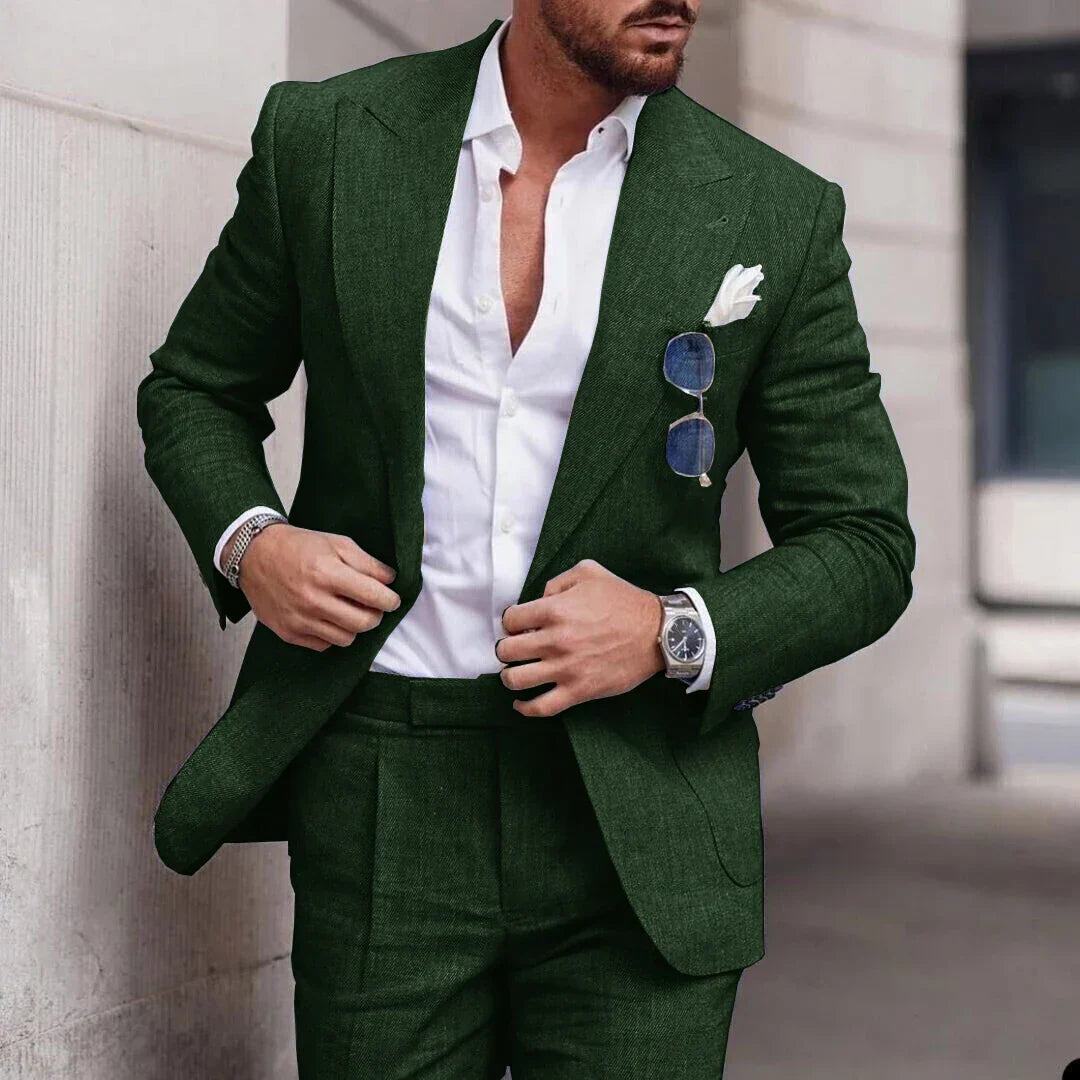 Homme en costume vert élégant, chemise blanche, lunettes de soleil accrochées, montre argentée, style mode masculine moderne, extérieur urbain.