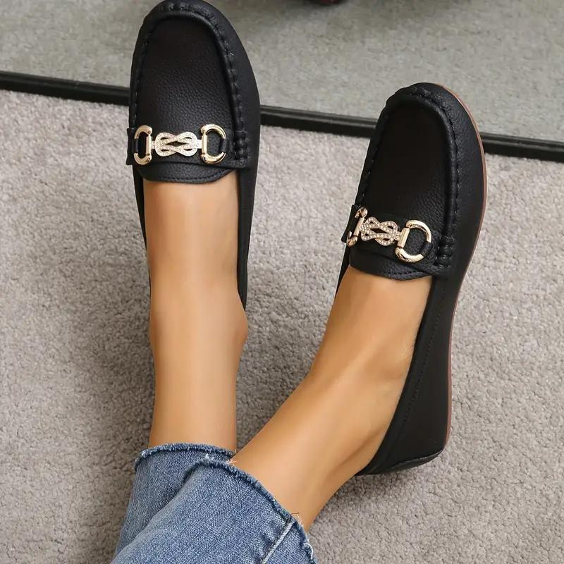 Mocassins noirs en cuir pour femme avec boucle dorée, portés avec un jean. Chaussures élégantes et confortables pour un style décontracté chic.