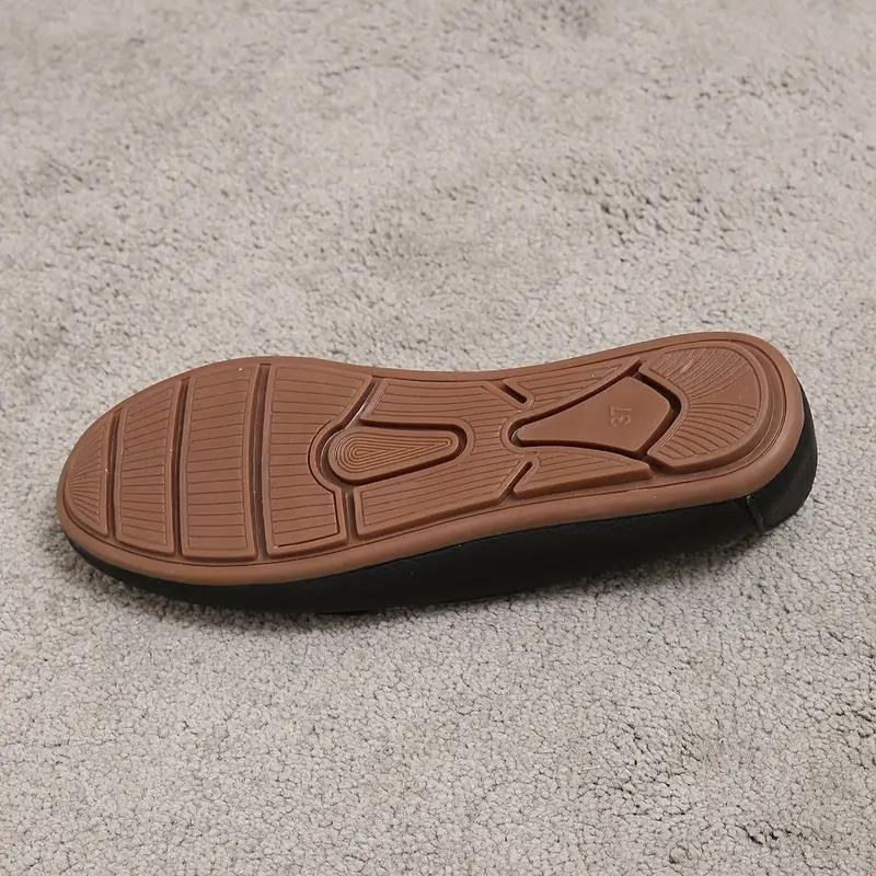 Semelle de chaussure en caoutchouc marron sur tapis gris, montrant des motifs antidérapants. Idéal pour confort et adhérence.