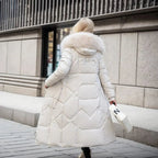 Femme en manteau long blanc avec capuche en fourrure, marchant en ville, tenant un sac blanc. Mode hiver, élégance urbaine, tendance féminine.