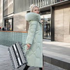 Femme en manteau d'hiver vert avec col en fourrure, tenant un sac à rayures noir et blanc, marchant en ville. Mode hiver, élégance urbaine.