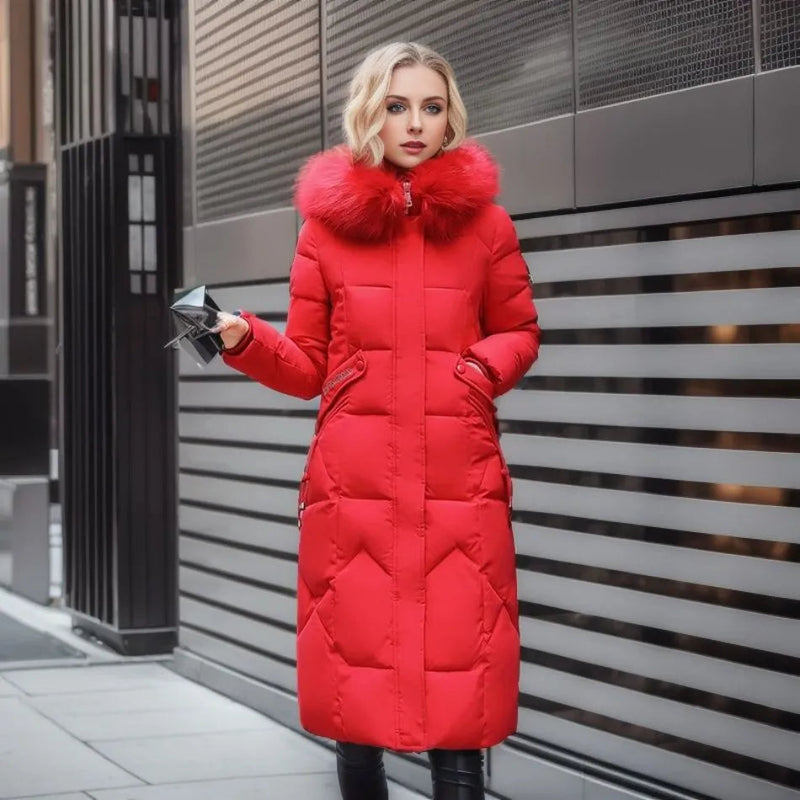 Femme portant un manteau d'hiver rouge avec col en fourrure, tenant un smartphone, devant un mur moderne. Mode hiver, élégance urbaine.