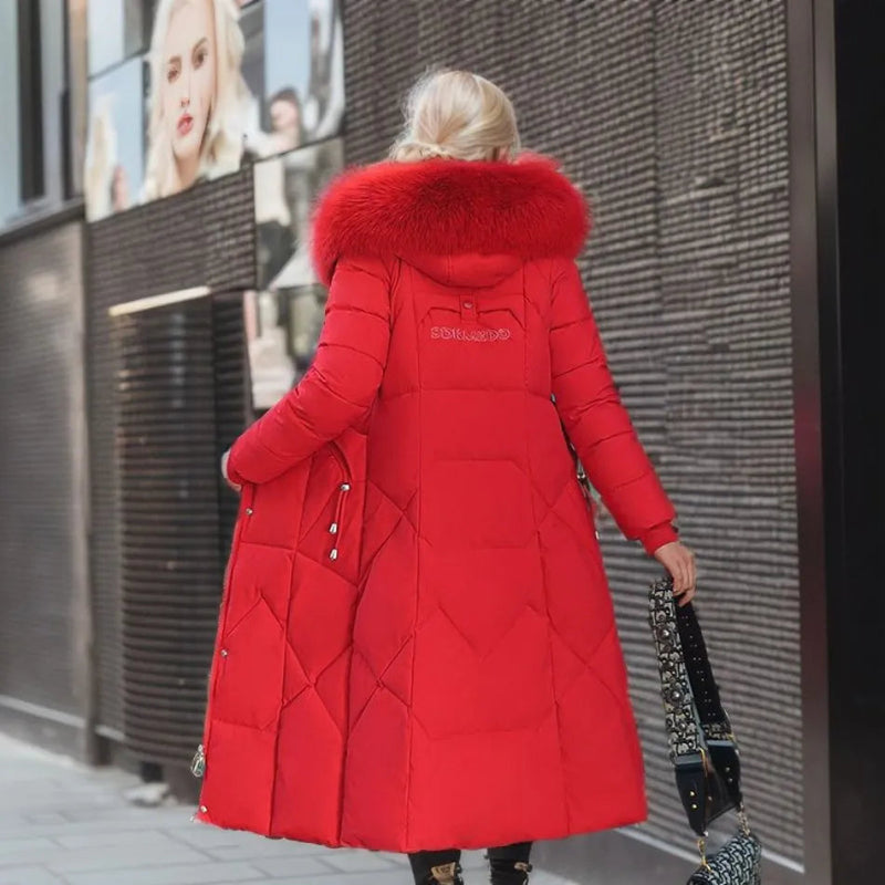 Femme portant un manteau long rouge avec capuche en fourrure, marchant en ville. Mode hiver élégante, tendance manteau chaud, style urbain chic.