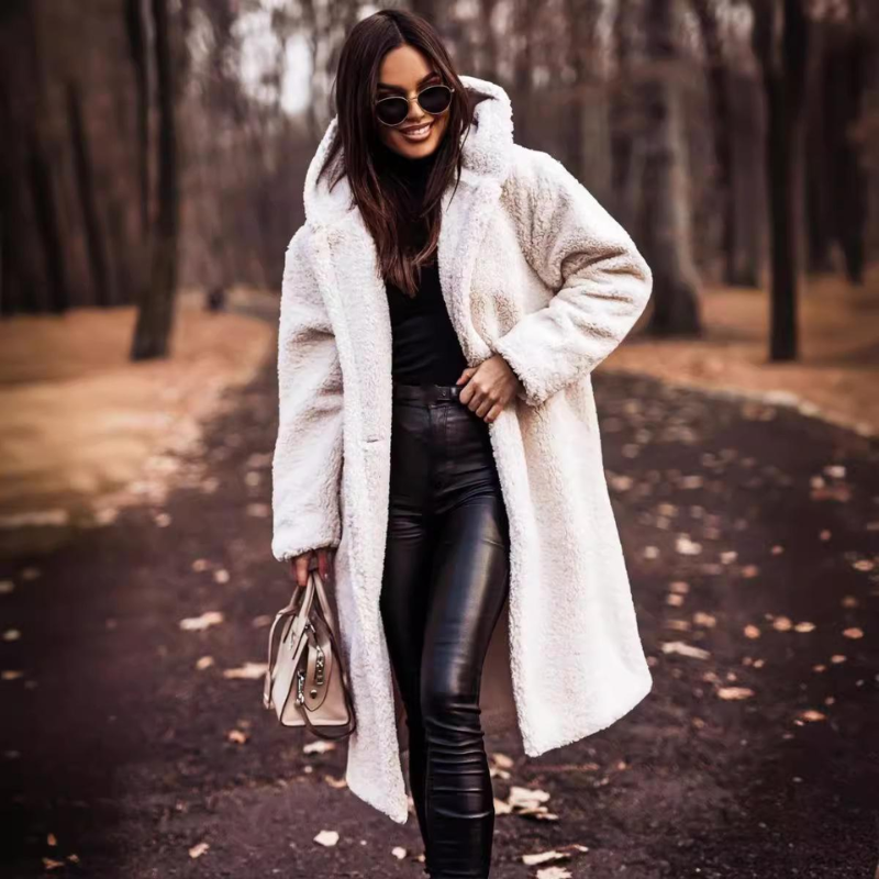 Femme élégante en manteau en fausse fourrure blanche, lunettes de soleil, pantalon en cuir noir, marchant dans un parc automnal. Mode hiver chic.