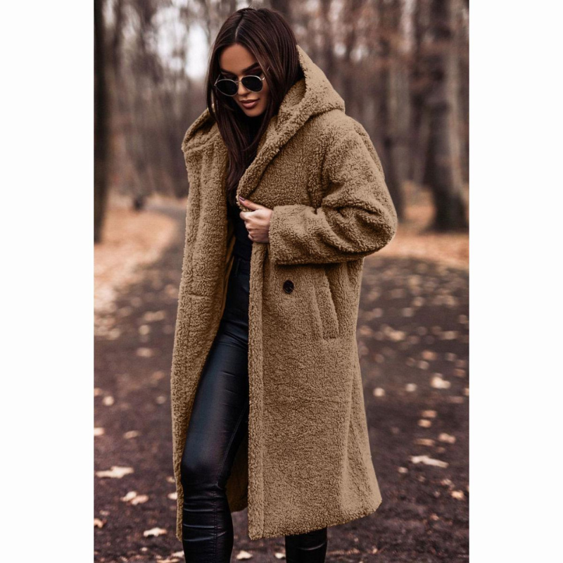 Femme portant un manteau en fausse fourrure marron, lunettes de soleil, dans un parc automnal. Mode hiver, style chic, promenade en forêt.