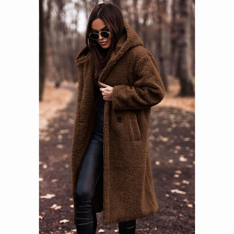 Femme portant un manteau en fausse fourrure marron, lunettes de soleil, marchant dans un parc automnal. Mode hiver, style chic, tendance.