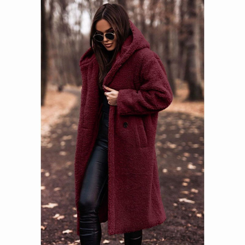 Femme portant un manteau en laine bouclée bordeaux, lunettes de soleil, dans un parc automnal. Mode hiver, style élégant, tendance féminine.