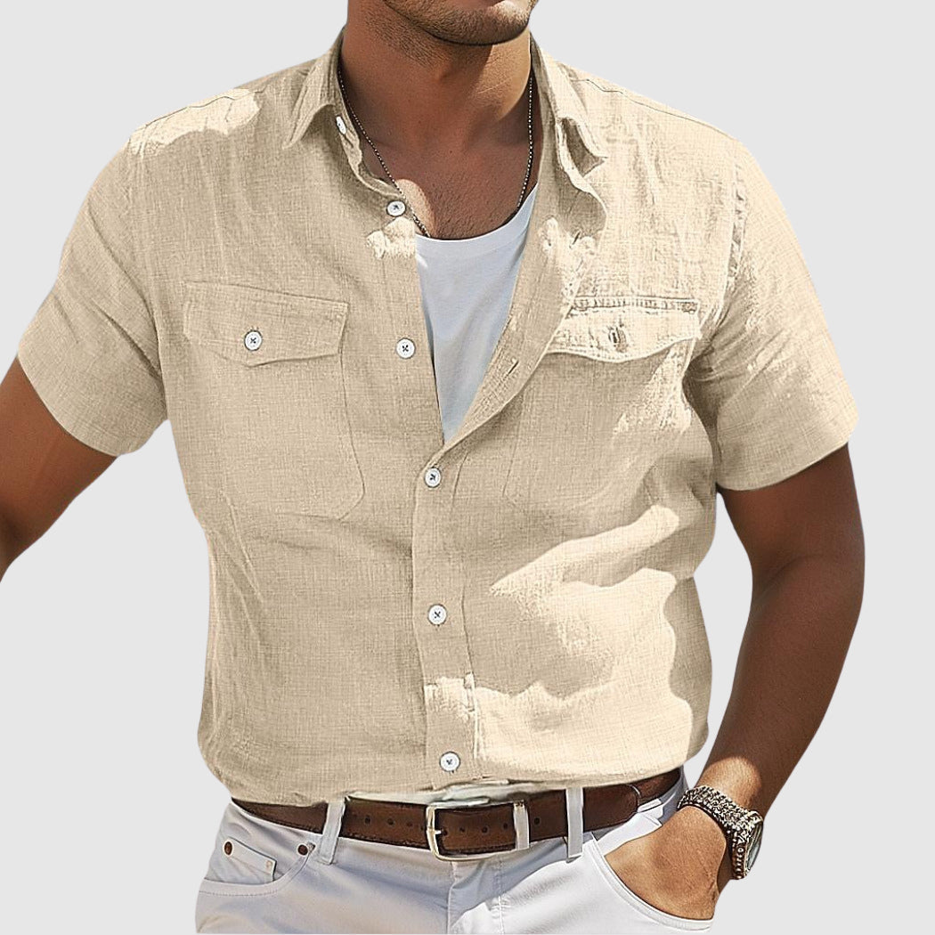 Homme portant une chemise beige à manches courtes, col ouvert, avec une montre-bracelet. Mode décontractée estivale, style élégant et moderne.