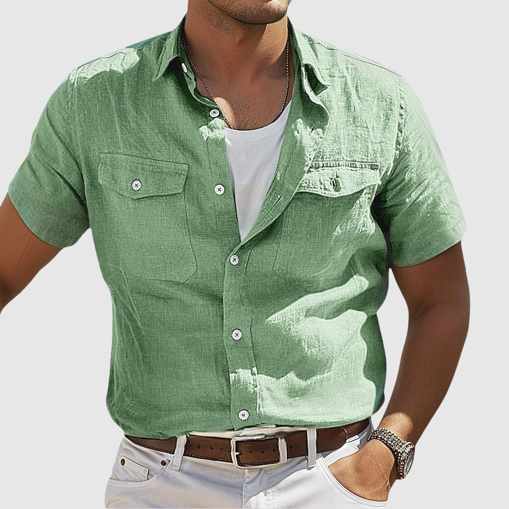 Homme portant une chemise verte en lin, manches courtes, avec poches, sur un t-shirt blanc, ceinture marron, style décontracté.