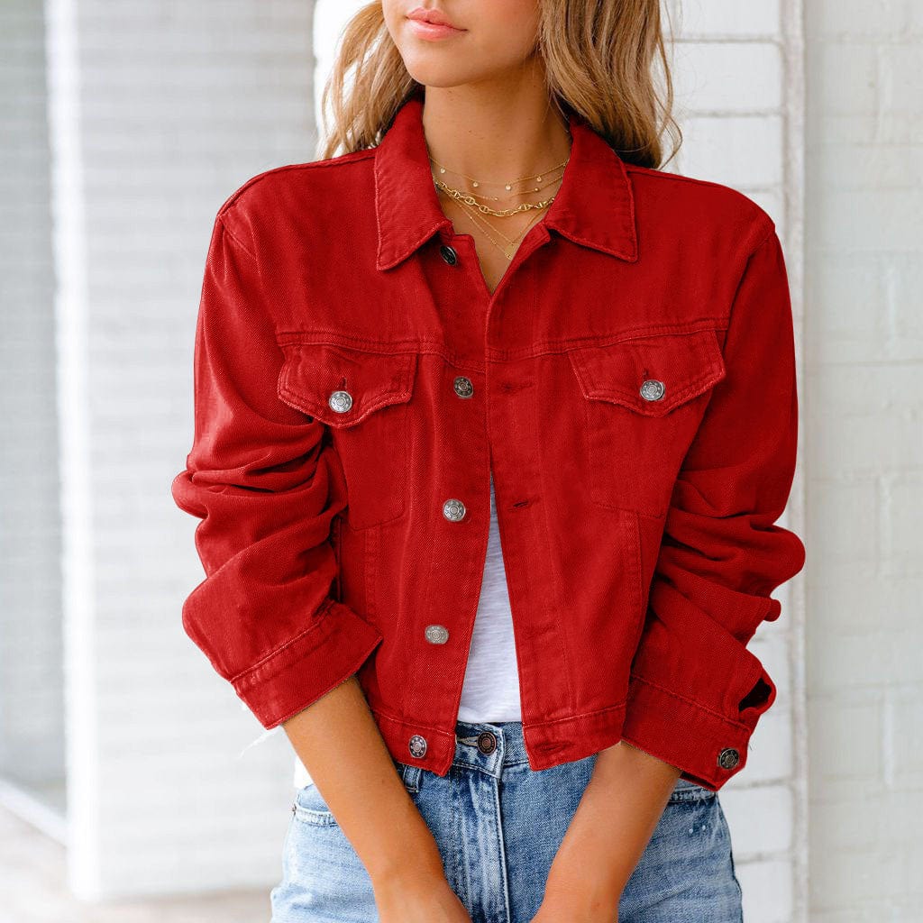 Femme portant une veste en jean rouge, manches retroussées, sur un t-shirt blanc, avec un collier doré, devant un mur blanc. Mode décontractée chic.