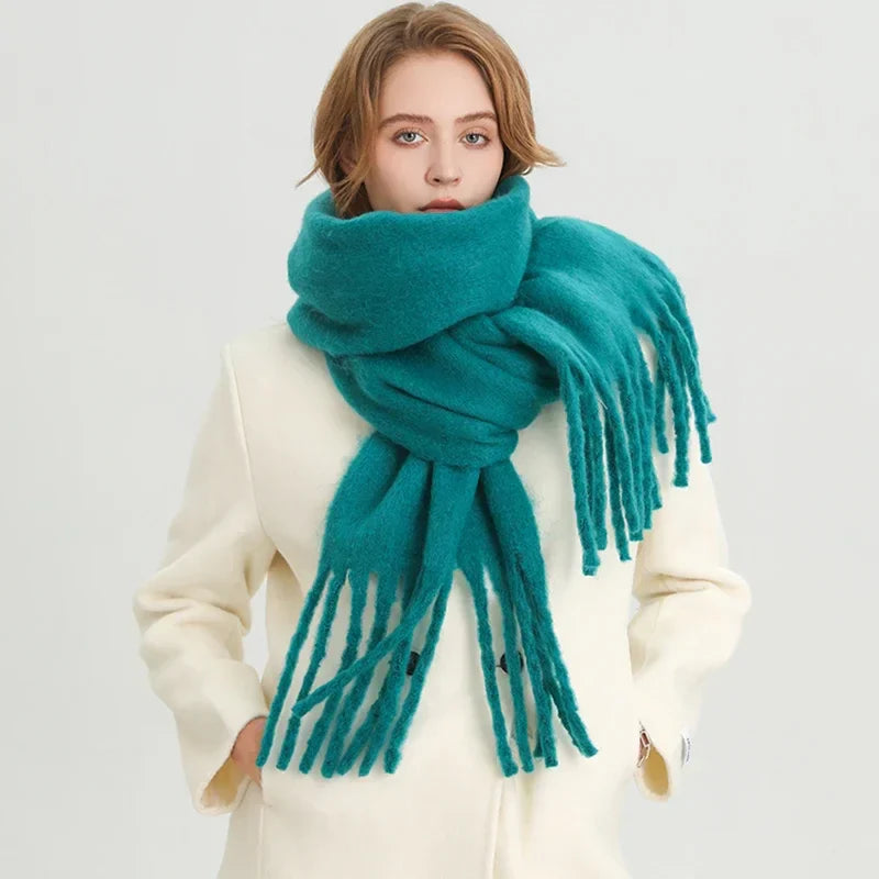 Femme portant une écharpe en laine turquoise sur un manteau blanc, mode hiver élégante, accessoire chaud et tendance, style moderne.
