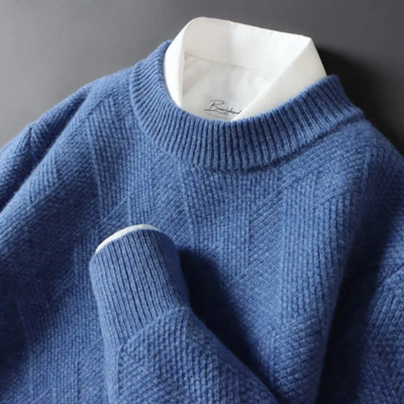 Pull bleu en laine texturée avec col rond, superposé sur une chemise blanche. Mode automne-hiver, style élégant et confortable.