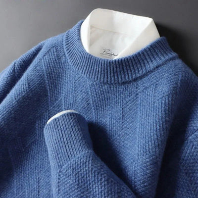 Pull bleu en laine texturée avec col rond, superposé sur une chemise blanche. Mode automne-hiver, style élégant et confortable.