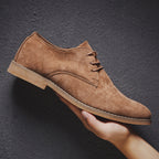 Chaussure en daim marron pour homme, style derby, semelle beige, tenue à la main. Chaussure élégante, mode masculine, cuir suédé.