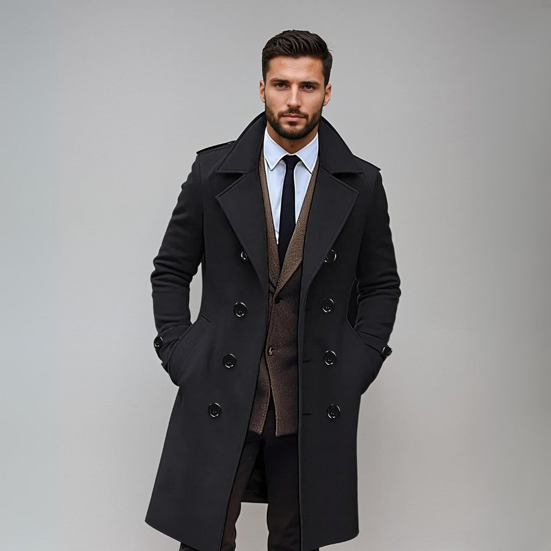 Homme élégant en manteau noir, costume marron et cravate, posant sur fond gris. Mode masculine, style formel, tendance automne-hiver.