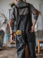 Homme en salopette grise avec gants de travail jaunes dans la poche arrière, intérieur moderne, style décontracté, bricolage, artisanat.