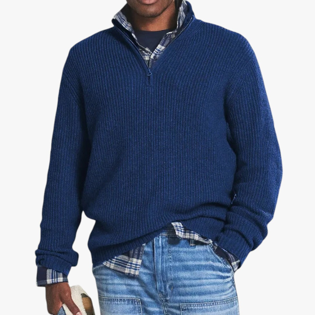 Homme portant un pull bleu en laine avec fermeture éclair, chemise à carreaux et jean décontracté. Mode masculine automne-hiver, style décontracté.