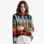 Femme portant un pull à carreaux multicolores, col roulé, manches longues, sur fond blanc. Mode automne-hiver, style décontracté et élégant.