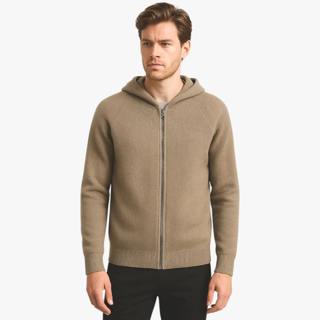 Homme portant un cardigan à capuche beige, fermeture éclair, sur fond blanc. Mode masculine, vêtement décontracté, style automne-hiver.