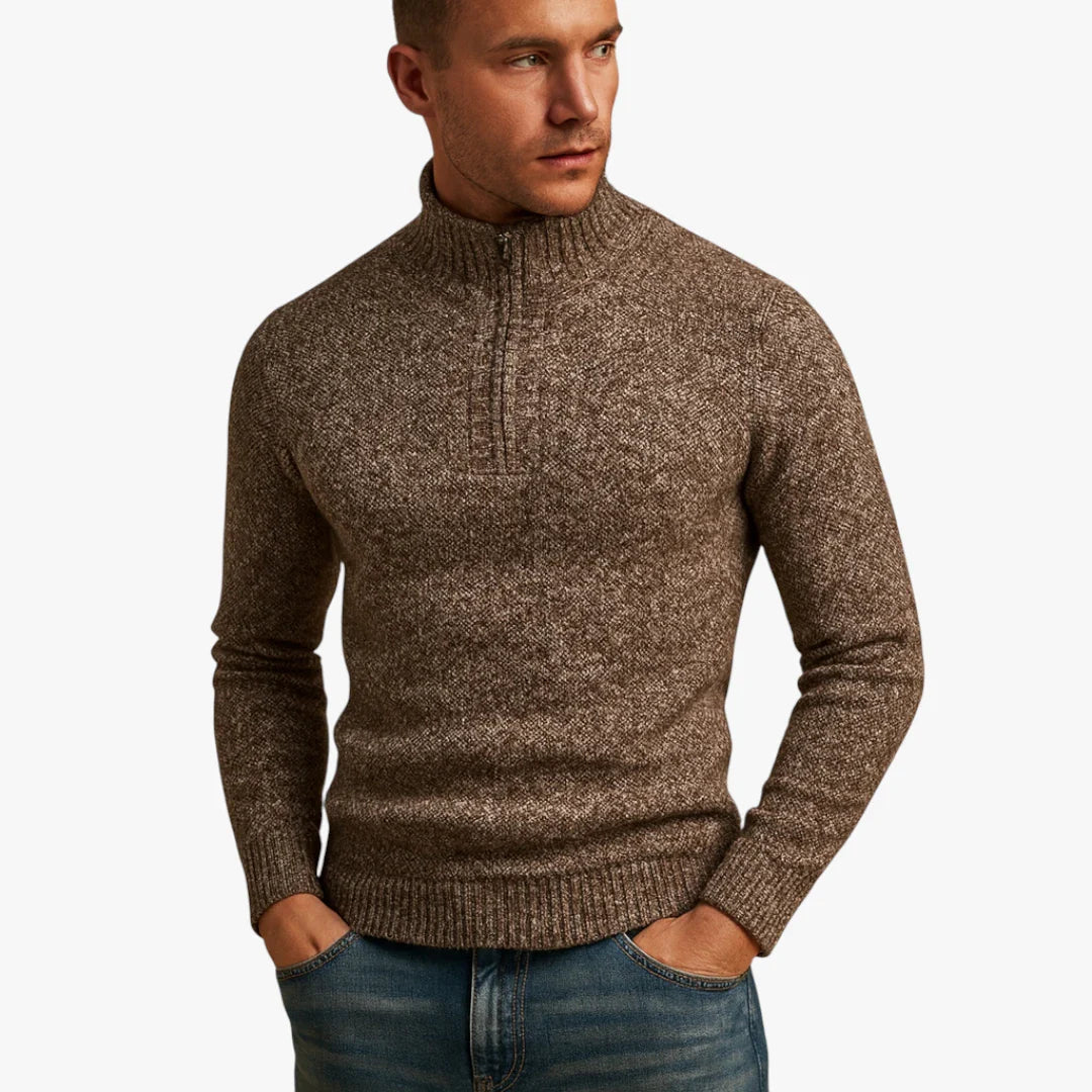 Homme portant un pull marron à col zippé, manches longues, en laine texturée, avec un jean bleu. Mode masculine automne-hiver, style décontracté.