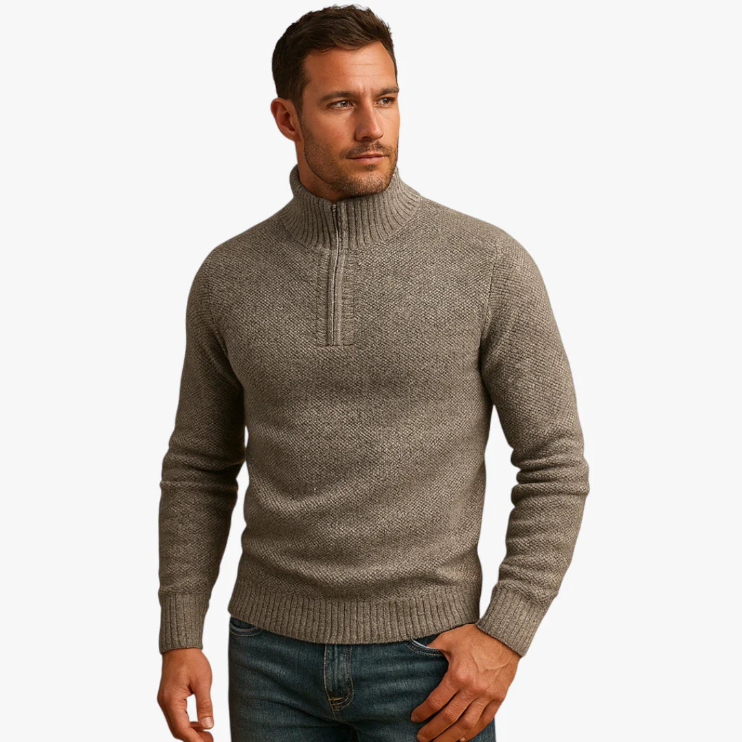 Homme portant un pull gris à col montant en laine, style décontracté, manches longues, avec fermeture éclair partielle, sur fond blanc.