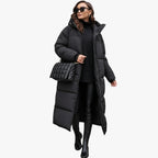 Femme portant un long manteau doudoune noir, pull noir, leggings en cuir, bottes noires, lunettes de soleil et sac à main matelassé noir.