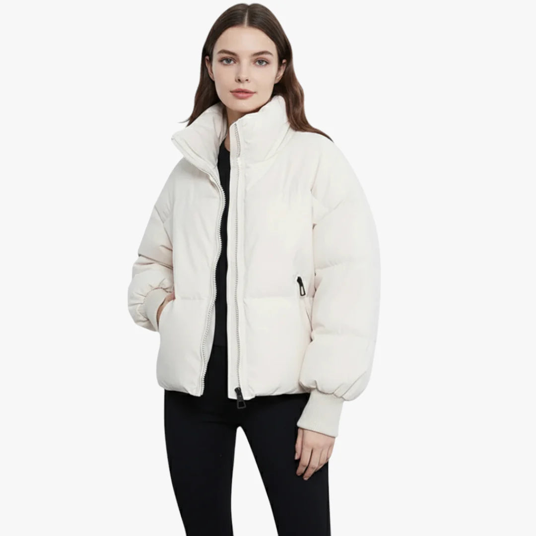 Femme portant une doudoune blanche élégante, fermeture éclair, col montant, manches longues, style hiver, mode féminine, tenue décontractée.