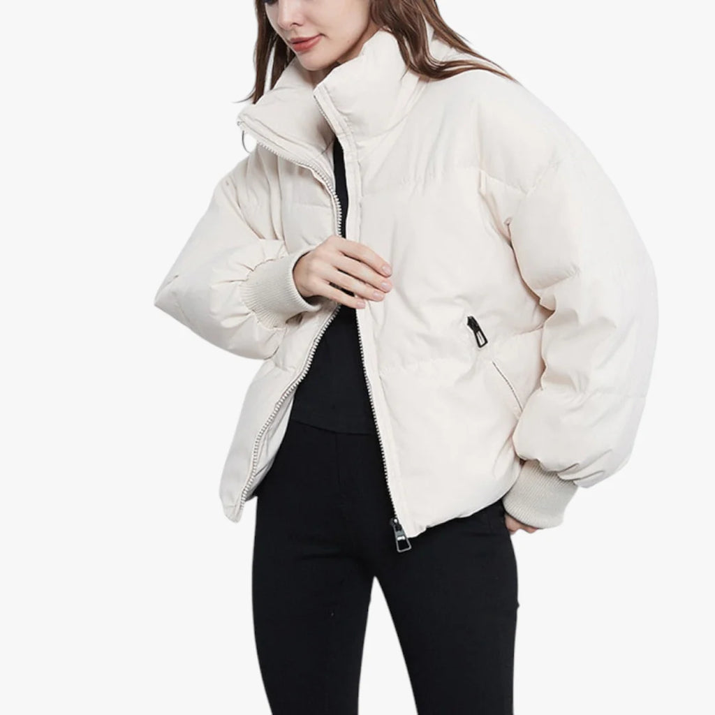 Femme portant une doudoune blanche, fermeture éclair ouverte, manches longues, col montant, sur fond blanc. Mode hiver, veste chaude, tendance.