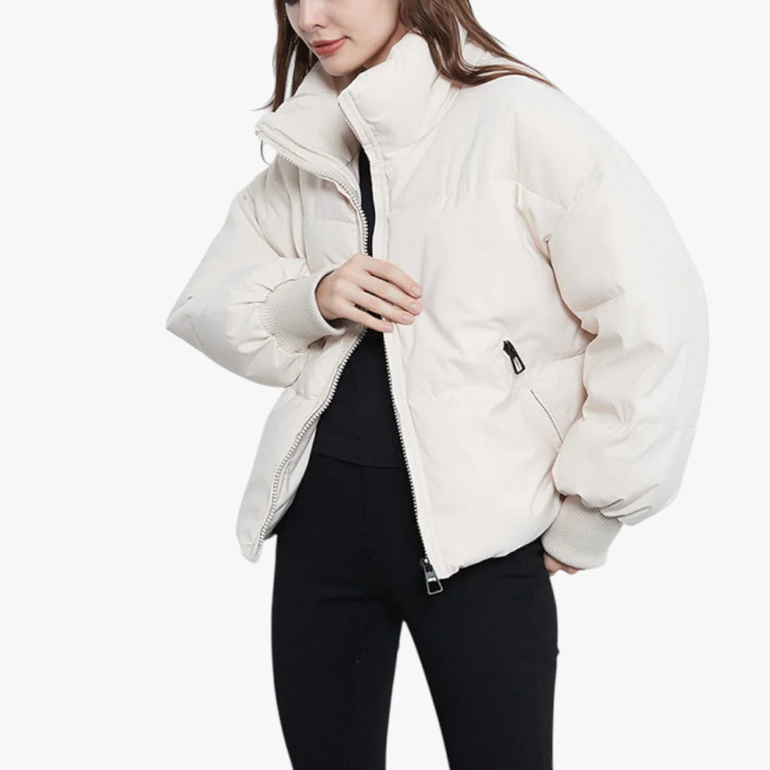 Femme portant une doudoune blanche, fermeture éclair ouverte, manches longues, col montant, sur fond blanc. Mode hiver, veste chaude, tendance.