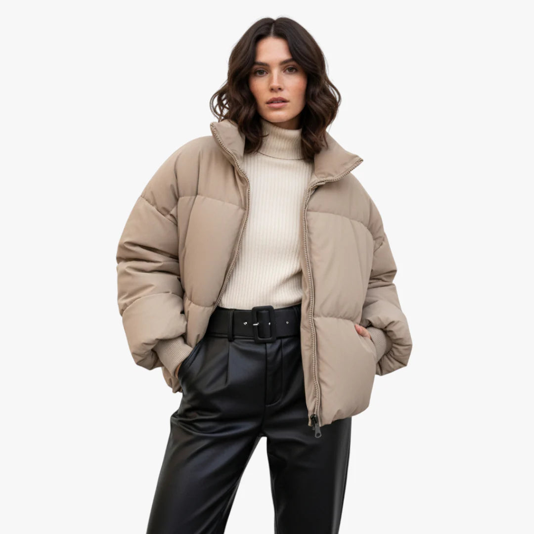 Femme portant une doudoune beige, pull col roulé crème et pantalon en cuir noir. Mode hiver élégante, tendance vestimentaire automne-hiver.