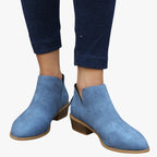 Bottines bleues en daim pour femme, talon bas, portées avec un jean foncé. Chaussures élégantes et confortables, tendance automne-hiver.