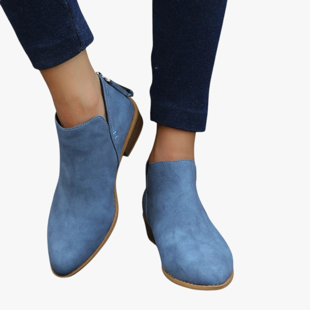 Bottines bleues en daim pour femme, élégantes et modernes, portées avec un pantalon en jean foncé. Chaussures tendance automne-hiver.