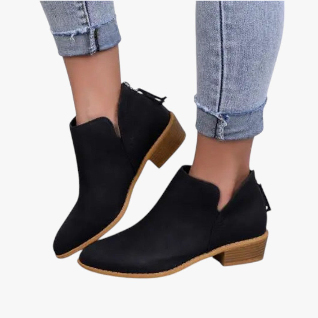 Bottines noires en daim pour femme avec talon bas, portées avec un jean décontracté. Chaussures tendance automne-hiver, style moderne et élégant.