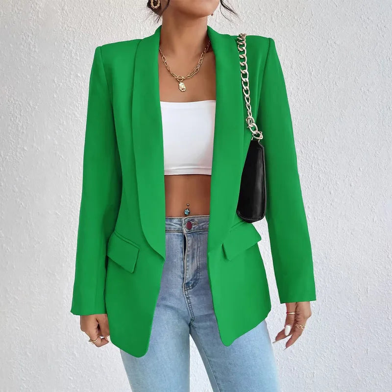 Femme portant un blazer vert élégant, top blanc, jean bleu et sac à chaîne dorée. Mode tendance, tenue chic, style moderne.