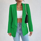 Femme portant un blazer vert élégant, top blanc, jean bleu et sac à chaîne dorée. Mode tendance, tenue chic, style moderne.