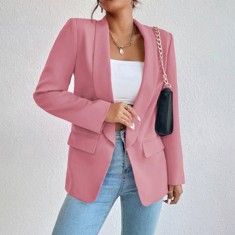Femme portant un blazer rose élégant, un top blanc et un jean bleu, accessoirisé d'un sac noir à chaîne dorée. Mode féminine chic et moderne.