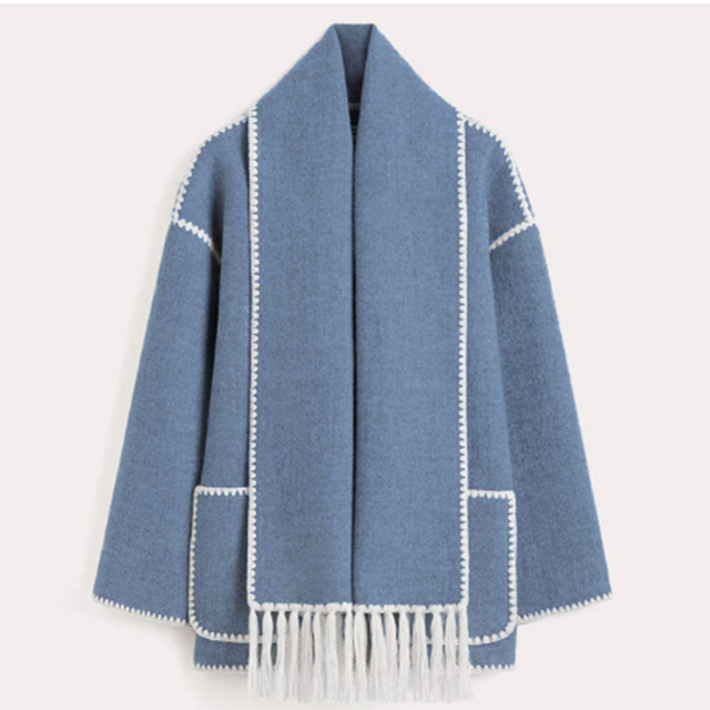 Veste en laine bleue avec bordures blanches et franges, style élégant et moderne, idéale pour l'hiver. Mode femme, tendance automne-hiver.