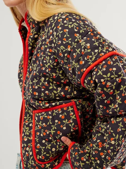 Veste matelassée à motifs floraux colorés, bordure rouge, manches longues, poches avant, style automne-hiver, mode féminine tendance.