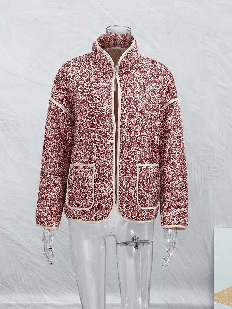 Veste matelassée rouge à motifs floraux blancs, col montant, poches avant, sur mannequin transparent. Mode automne-hiver, style élégant et confortable.
