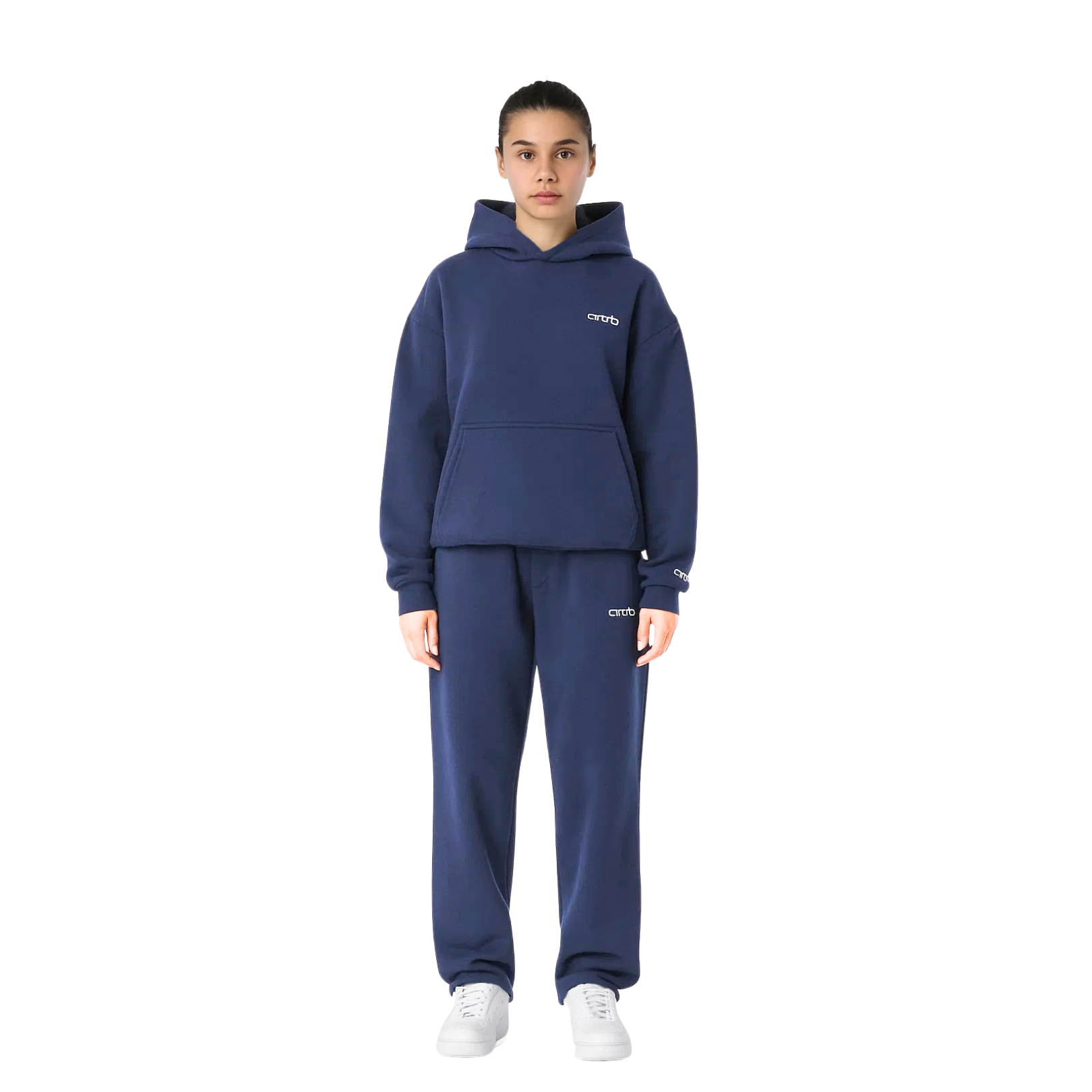 Jeune femme portant un ensemble de survêtement bleu marine avec capuche, logo "OTRO" visible, baskets blanches. Mode décontractée, tendance streetwear.