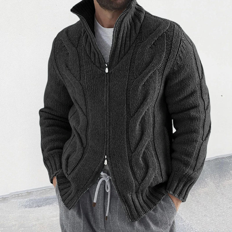 Homme portant un cardigan en tricot torsadé gris foncé avec fermeture éclair, col montant, manches longues, style décontracté. Mode masculine automne-hiver.