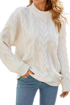 Femme portant un pull torsadé blanc en laine, manches longues, col rond, associé à un jean bleu. Mode automne-hiver, style décontracté élégant.